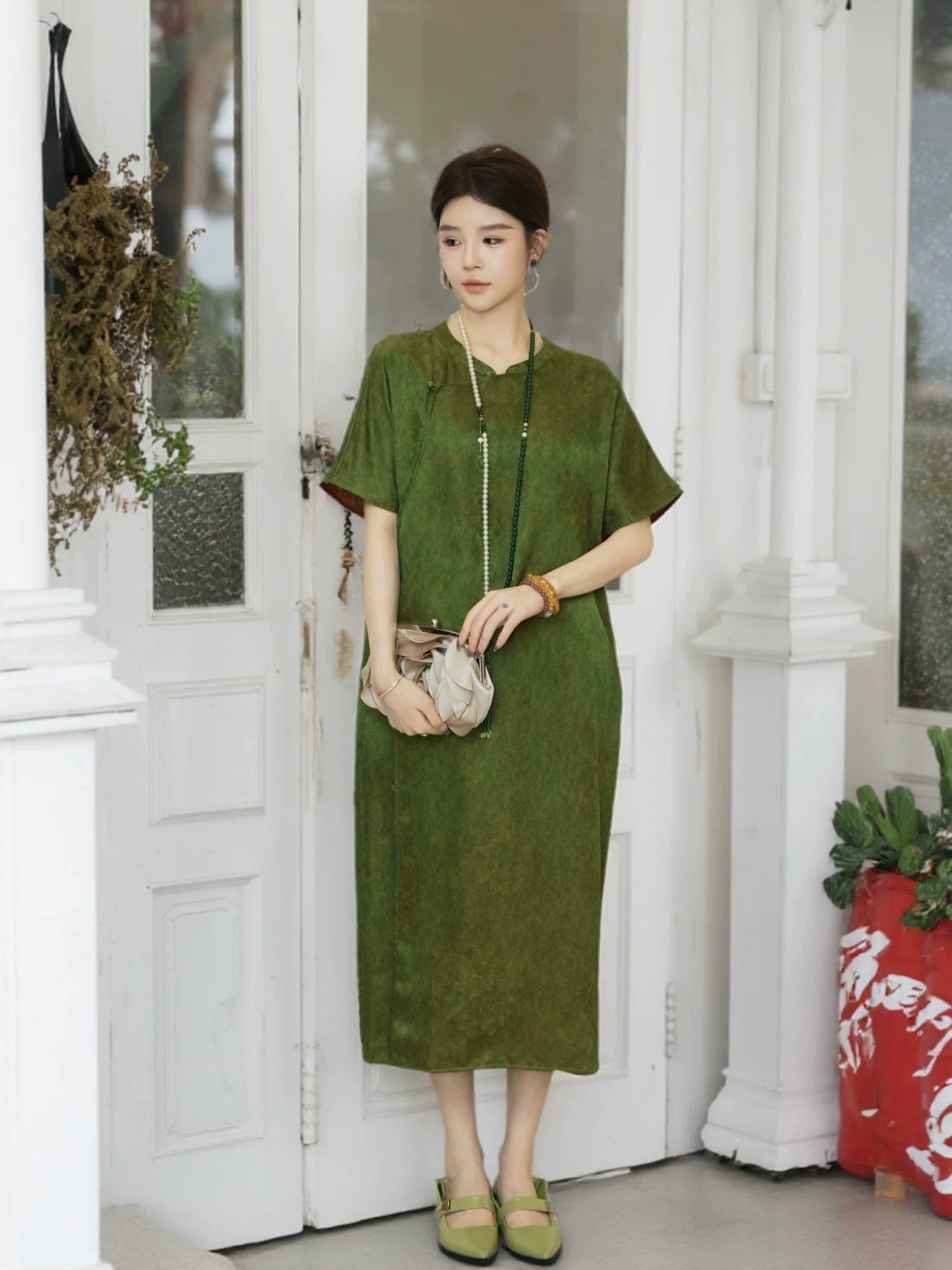 Model wearing an olive green Chinese-inspired dress with a natural waist and subtle floral texture