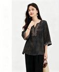 Side view of a green silk blouse with three-quarter sleeves and colorful bohemian-style embroidery, showcasing the soft drape and breathable 100% silk material.
