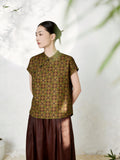 Side view of an olive green silk Cheongsam top with a mandarin collar, short sleeves, and all-over geometric jacquard pattern, featuring traditional side button details, crafted from 100% mulberry silk, paired with a brown pleated skirt.
