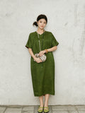 Model wearing a relaxed olive green H-line silk dress with regular sleeves in a lifestyle setting