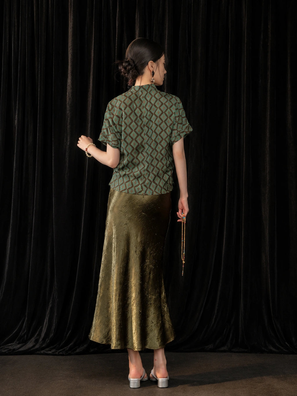 Back view of the olive green high-sheen fishtail skirt styled with a short Chinese-style top