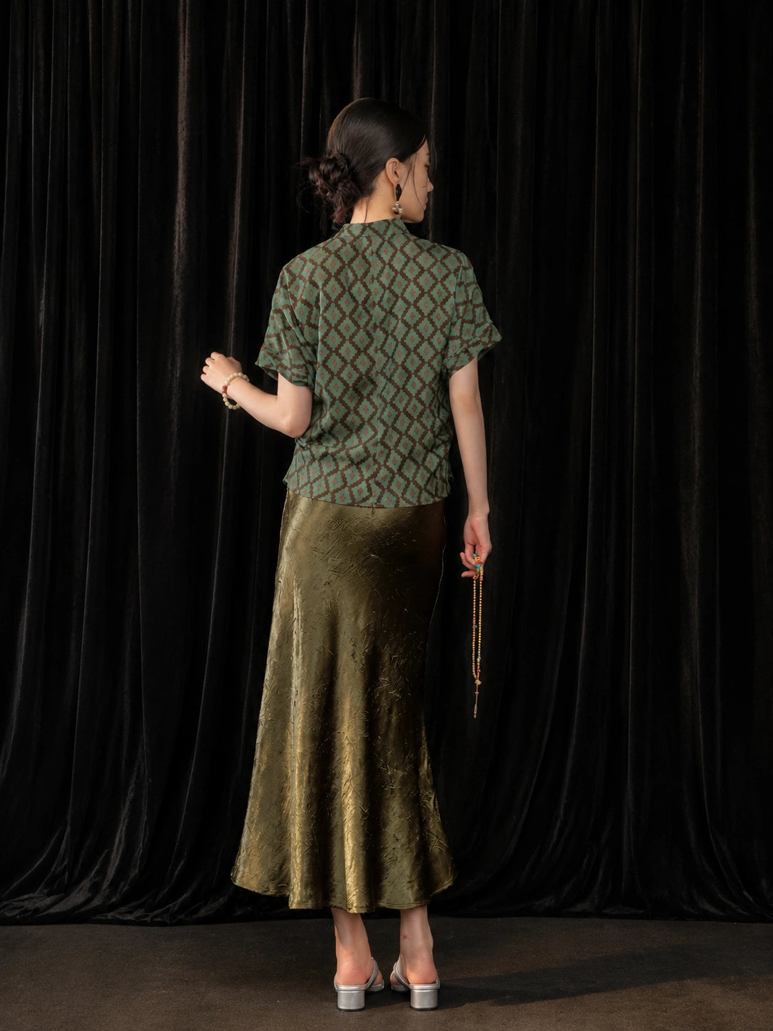 Back view of the olive green high-sheen fishtail skirt styled with a short Chinese-style top