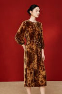 Model wearing the copper-orange midi dress from a three-quarter angle
