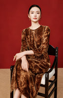 Seated model wearing the copper-orange tie-dye-inspired midi dress