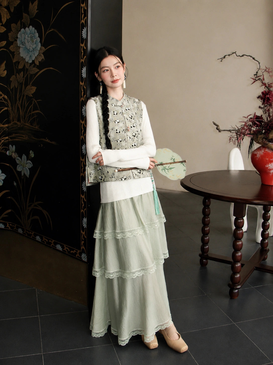 Full-body styling of a pale green Shu Jin silk vest paired with a tiered lace-trimmed skirt.
