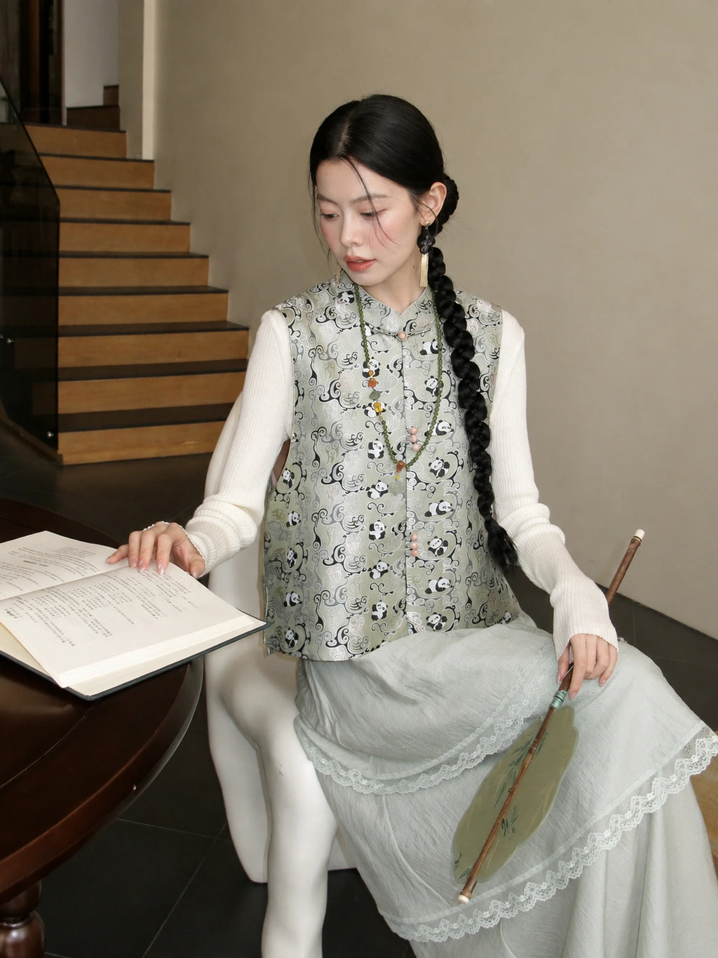 Close-up of a pale green mulberry silk vest showing its bear pattern, stand collar, and decorative closures.