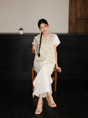 Seated model wearing a round-neck floral mulberry silk vest with a traditional Chinese-inspired design.