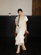 Seated model wearing a round-neck floral mulberry silk vest with a traditional Chinese-inspired design.