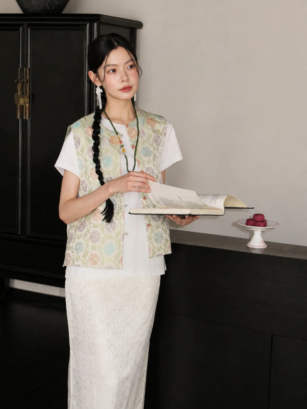 Model wearing a pastel floral Songjin silk Chinese vest over a white top and ivory skirt.