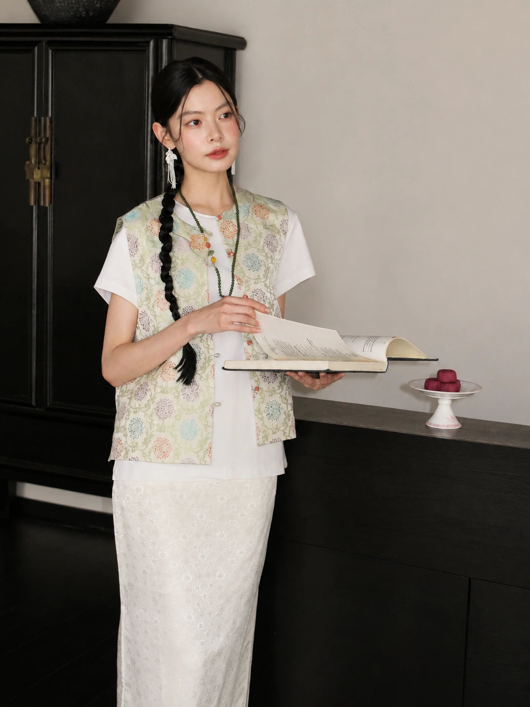 Model wearing a pastel floral Songjin silk Chinese vest over a white top and ivory skirt.