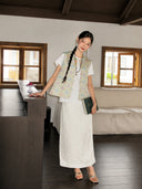 Full-body view of a pastel floral Songjin silk vest styled with an ivory long skirt.