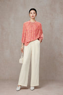 Full-length styling of the peach pink blouse with wide-leg cream trousers