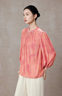 Side profile highlighting the puff sleeve and curved hem of the pink blouse