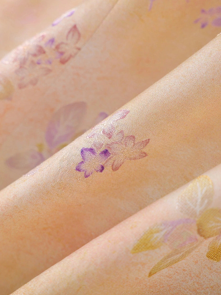 Close-up of peach viscose fabric with a soft watercolor effect and delicate purple floral print.