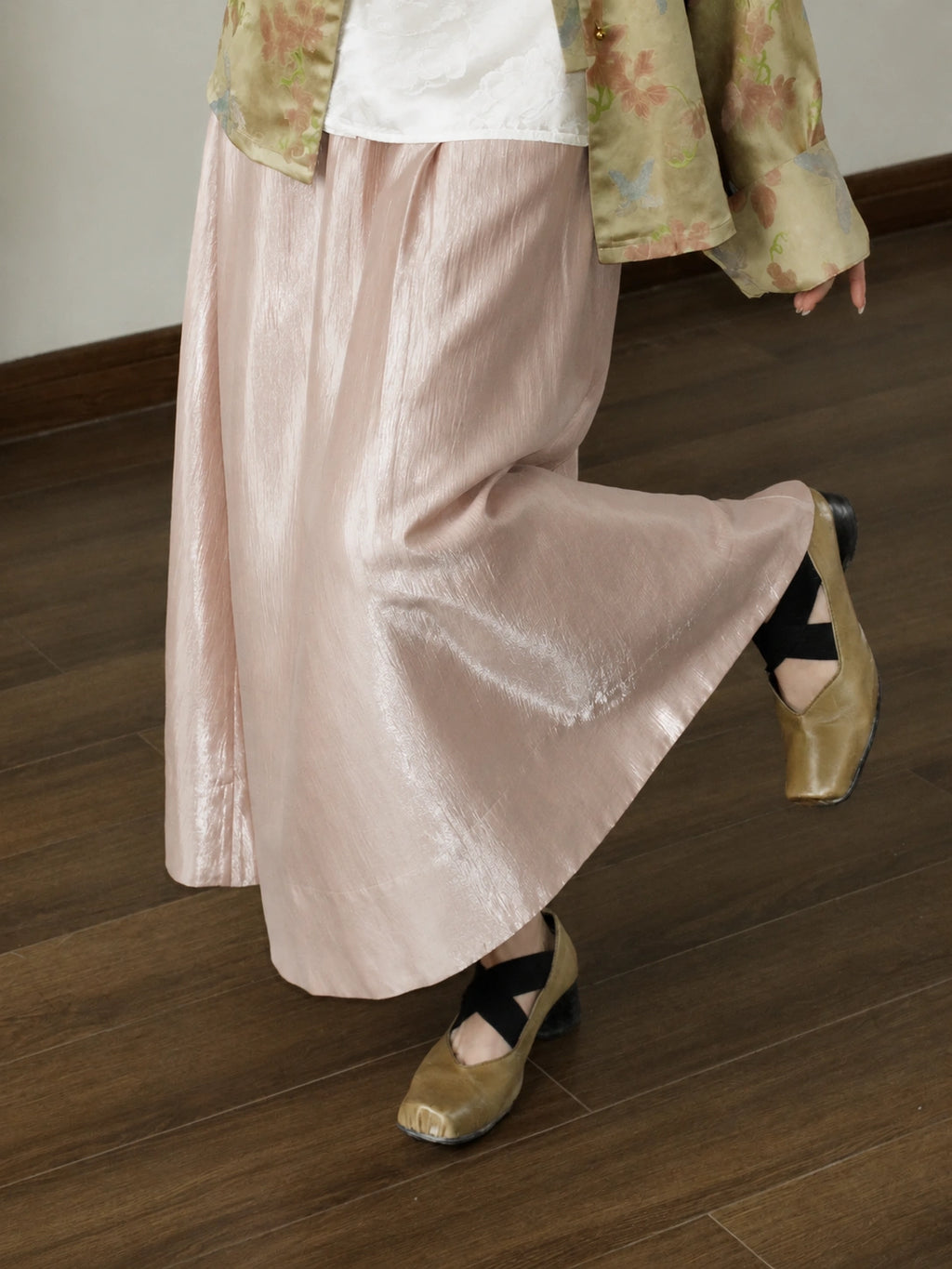 Detail view of a pink high-waist A-line skirt with a soft glossy acetate-lyocell blend finish, styled with a white top and tan shoes.