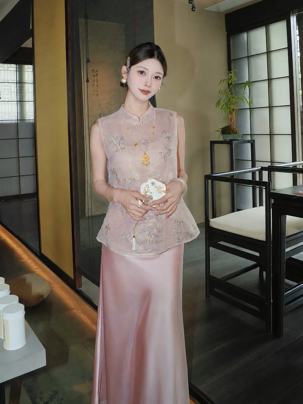 Front view of a pink Cheongsam vest with floral sequin embroidery, paired with a pink satin skirt, standing in a traditional interior setting.