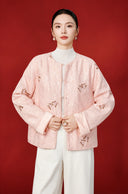 Model wearing the pink butterfly embroidered jacket open over a white turtleneck, showing its smooth turn-back cuffs.