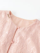 Close-up of the pink jacket’s round neckline, matching piping, buttons and textured fabric.