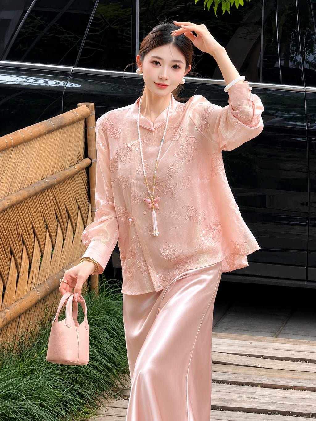 Model wearing a pink embroidered top and matching satin skirt, holding a pink handbag, highlighting the flowy and elegant silhouette.