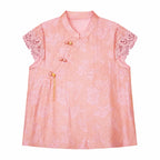 Flat lay of a pink jacquard blouse with a mandarin collar, lace cap sleeves, and a side button closure, crafted from 80% Viscose and 20% Polyamide.