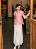 Side view of a pink Cheongsam-style top with delicate lace sleeves and side slits, paired with white pleated pants, crafted from a Viscose-Polyamide blend.