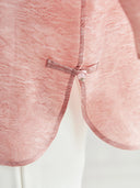 Close-up of a pink silk-blend top featuring a traditional frog button closure, showcasing the intricate texture and craftsmanship.