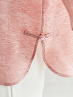 Close-up of a pink silk-blend top featuring a traditional frog button closure, showcasing the intricate texture and craftsmanship.