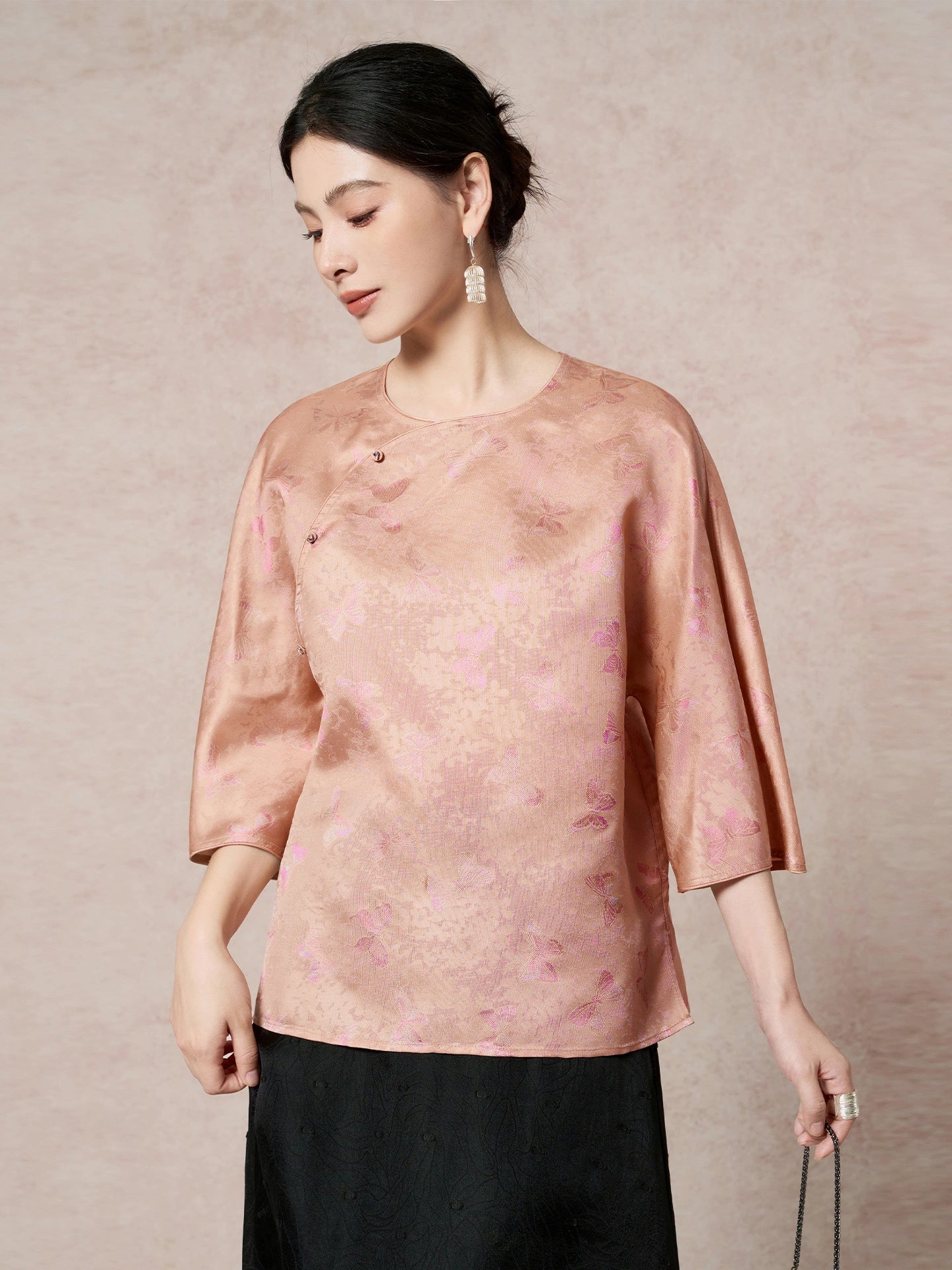 Side view of a pink-gold silk blouse with a relaxed fit and side button details, showcasing the luxurious 100% mulberry silk fabric.
