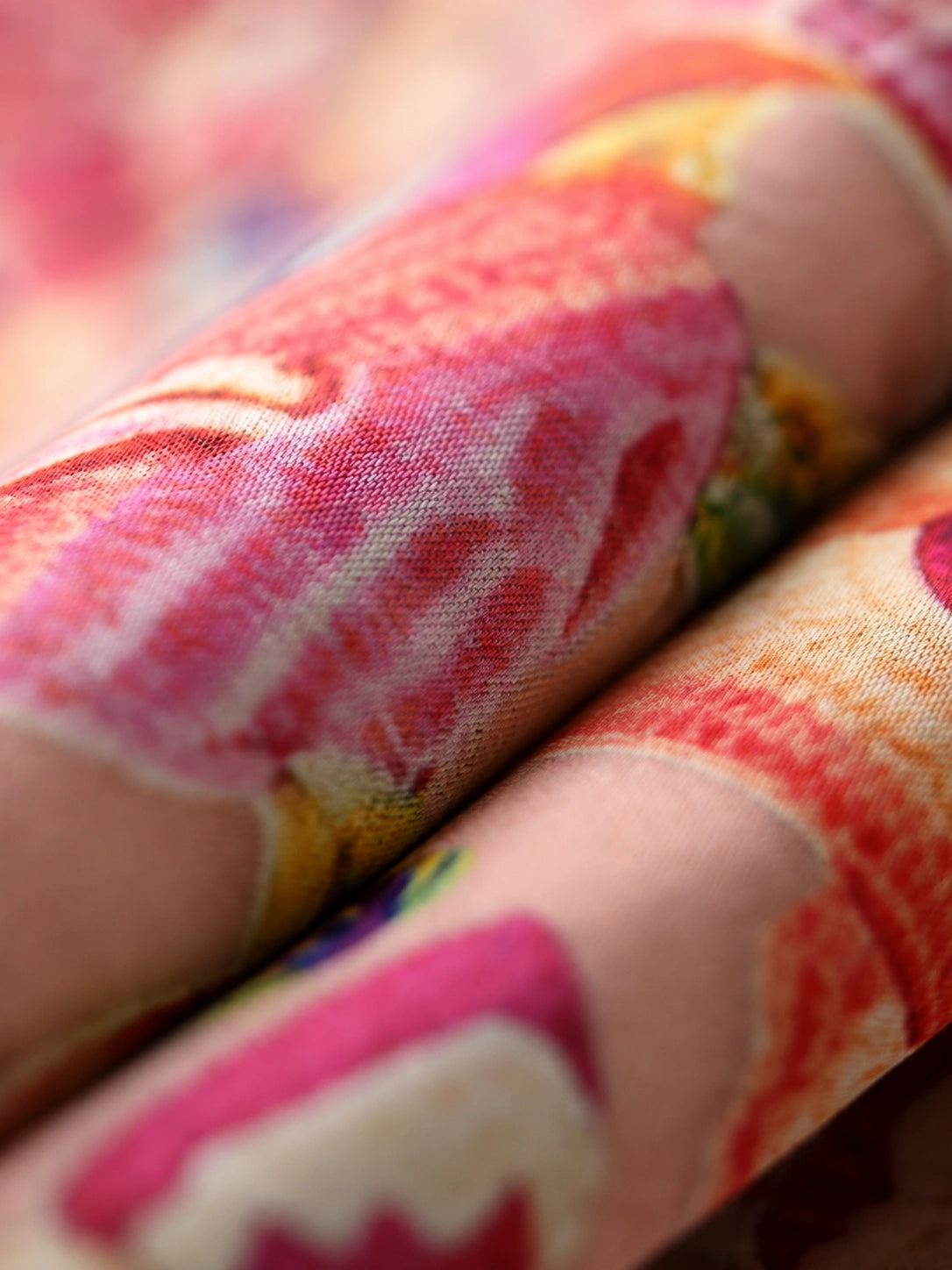Close-up of the lustrous pink Xiangyunsha fabric with colorful koi and floral motifs