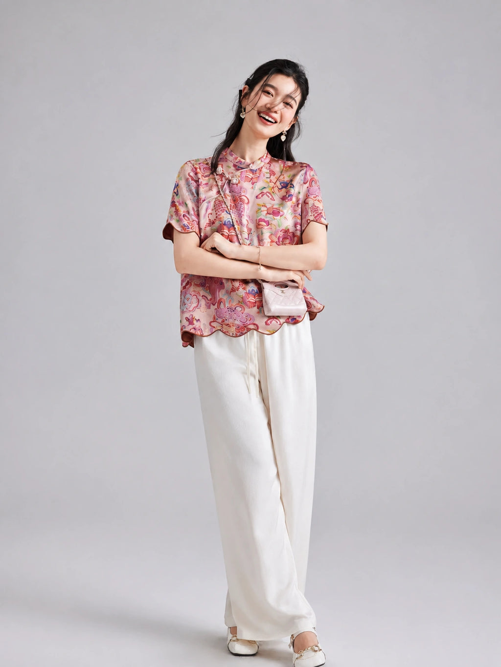 Woman wearing a pink koi and floral Xiangyunsha short-sleeve top with white wide-leg trousers