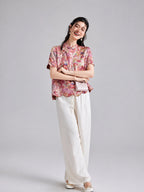 Woman wearing a pink koi and floral Xiangyunsha short-sleeve top with white wide-leg trousers
