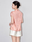 Back view of a model wearing a relaxed pink floral blouse with cap sleeves and a Mandarin collar.