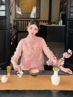 Close-up of a pink sleeveless vest with metallic embroidery, styled with a pink skirt and a white tea cup, highlighting the intricate details.