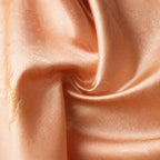 Close-up detail of pink mulberry silk fabric with subtle jacquard texture and elegant woven pattern