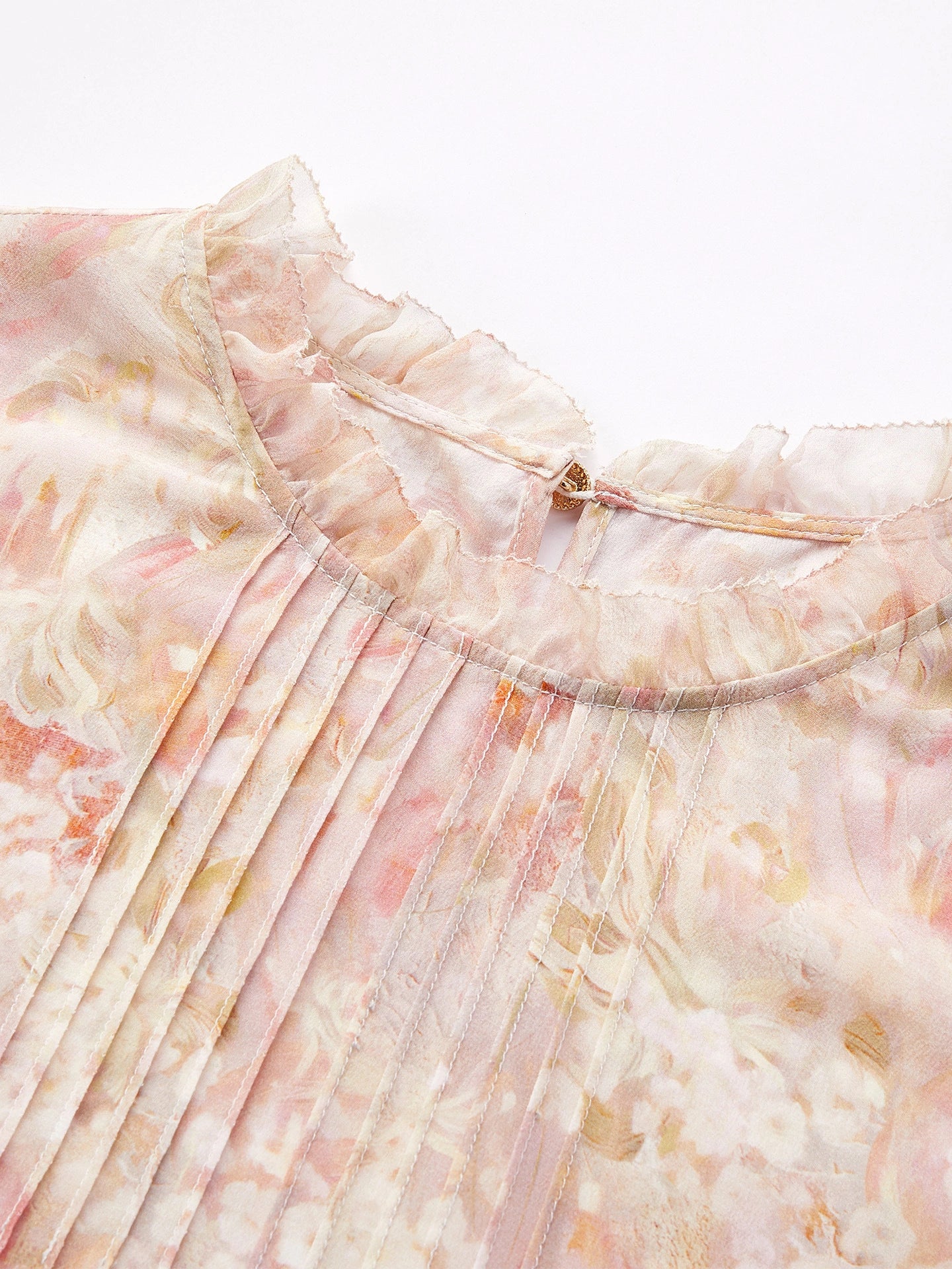 Close-up of a 100% mulberry silk blouse featuring a ruffled stand collar, delicate floral print, and fine pleating details.