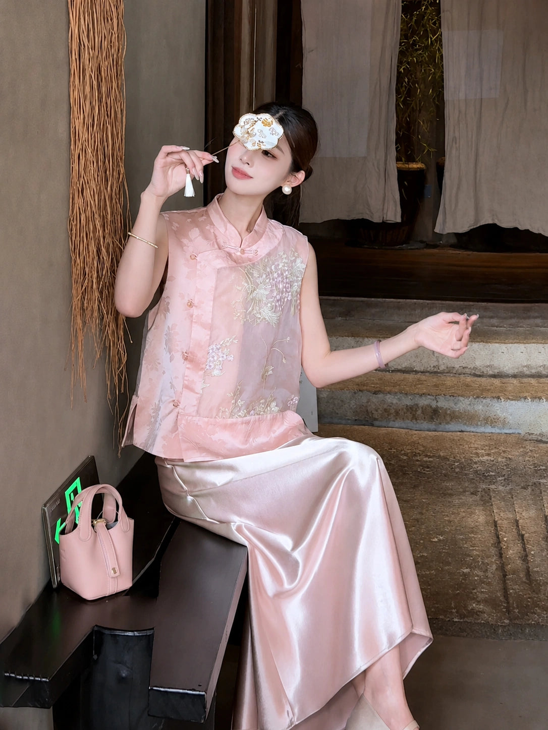 Sitting model in a pink satin A-line skirt, styled with a floral embroidered top and pink shoes, showcasing the elegant fabric sheen.