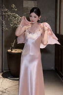 Model wearing a pink satin slip dress with a matching sheer jacket over her shoulders, featuring gold-tone strap hardware, 100% polyester fabric.
