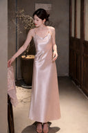 Full body shot of a pink satin slip dress with delicate spaghetti straps and a gentle cowl neckline, styled with open-toe sandals.