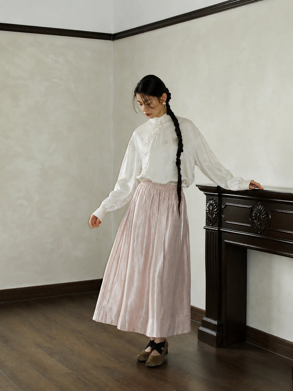 Styling image of a pink glossy high-waist A-line skirt with a white blouse, suitable for daily commuter wear.