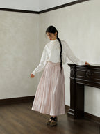 Styling image of a pink glossy high-waist A-line skirt with a white blouse, suitable for daily commuter wear.