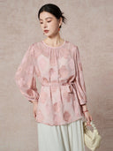 Full-body shot of a pink 100% silk georgette blouse featuring a waist tie, round neckline, and elegant vase cutwork embroidery.