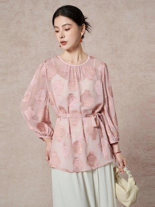 Full-body shot of a pink 100% silk georgette blouse featuring a waist tie, round neckline, and elegant vase cutwork embroidery.