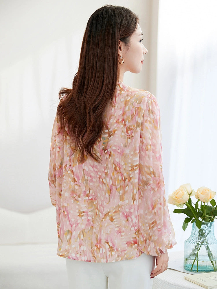 Back view of a pink abstract printed silk blouse with a relaxed fit and lantern sleeves, showcasing the beautiful drape and print from behind.