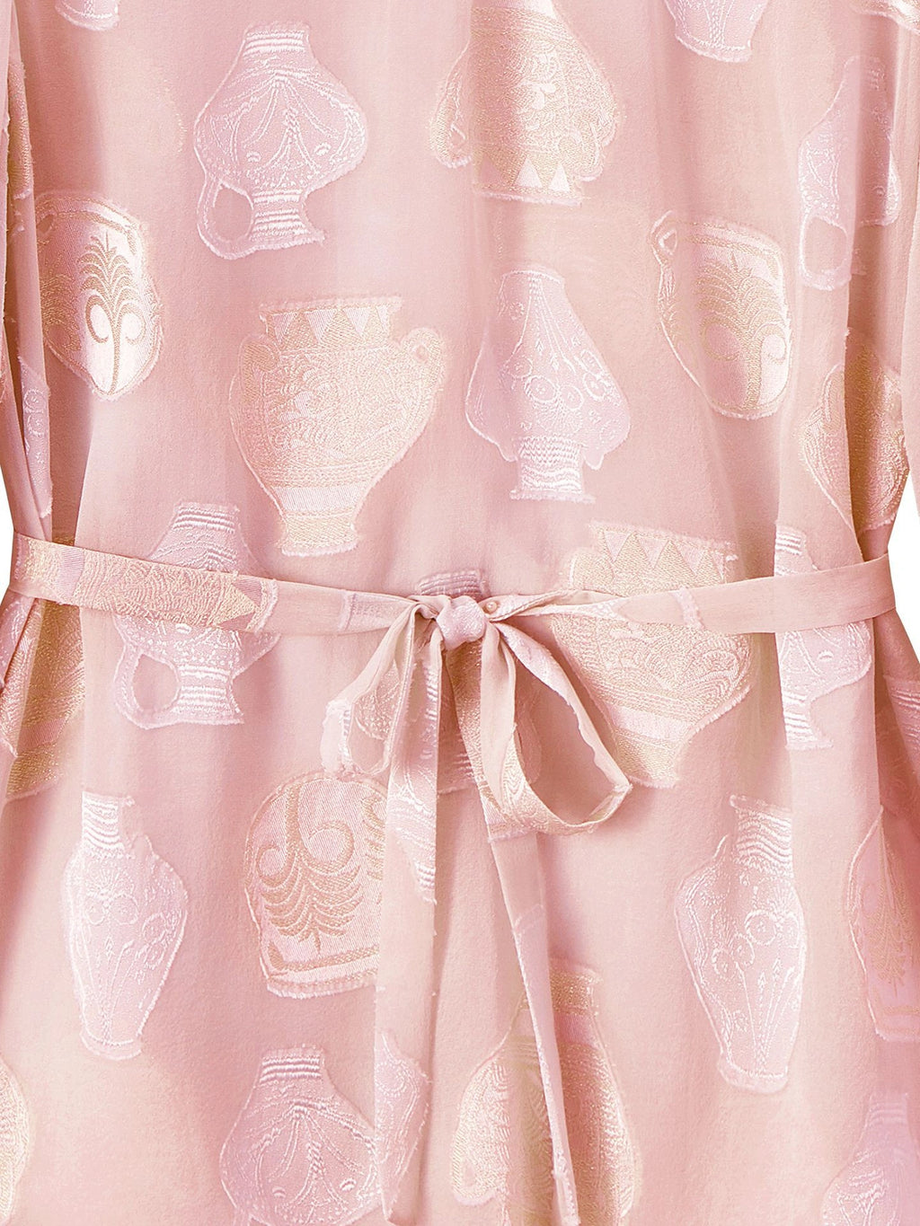 Close-up of a pink 100% mulberry silk blouse showing the sheer chiffon texture, white/silver cutwork vase pattern, and a matching silk tie belt.