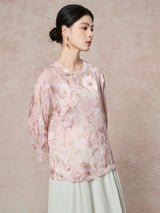 Front view of a pink 100% silk blouse with a round neckline and delicate floral embroidery, styled with a light green pleated skirt for a New Chinese look.