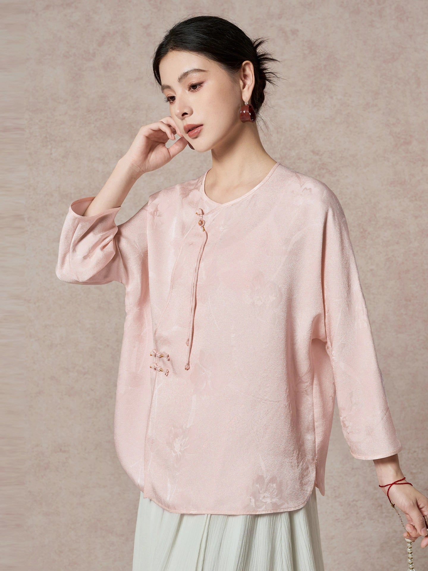 Side view of a pink silk blouse with a relaxed fit and a flowing drape, highlighting the elegant texture of the jacquard fabric.