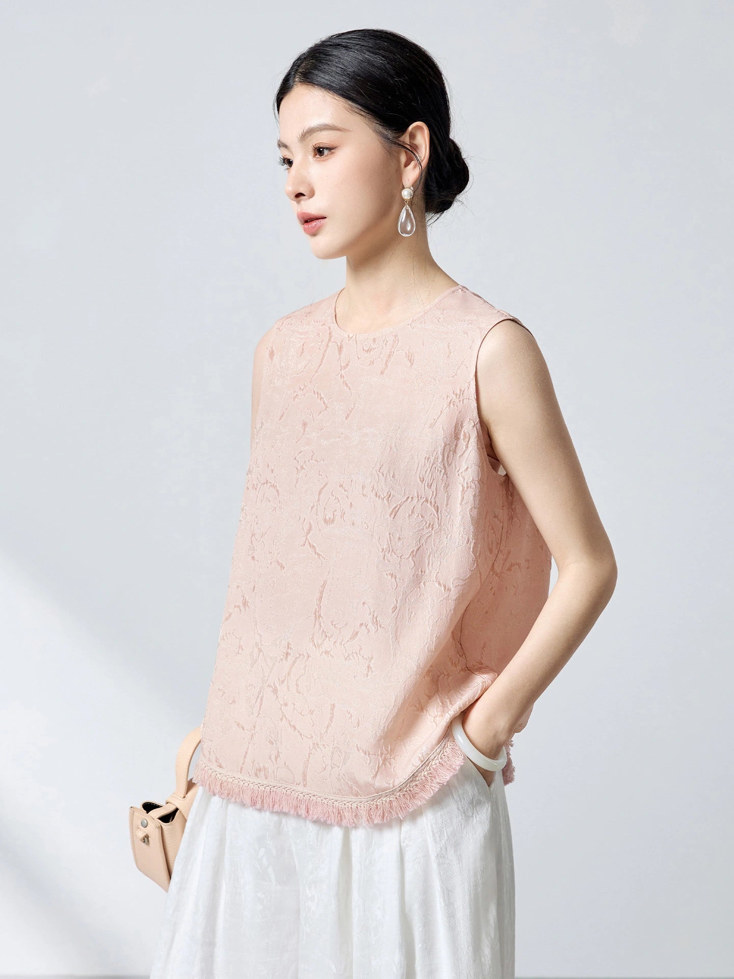 Side view of a pink silk top with a relaxed fit and jacquard texture, showcasing the elegant drape and handcrafted details.