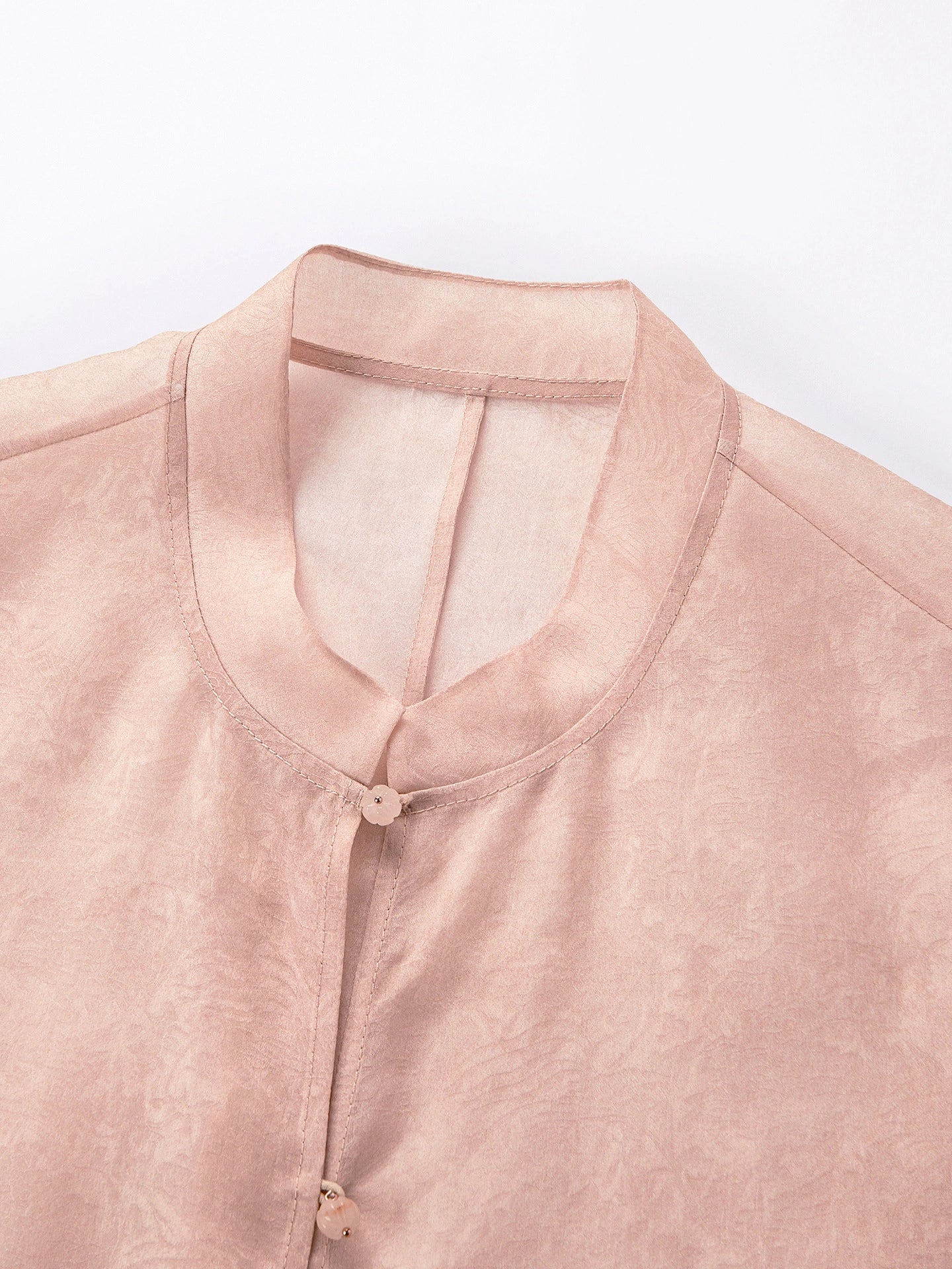 Close-up of the mandarin collar and front button closure on a pink 100% silk vest, highlighting the delicate cutwork embroidery and sheer texture.