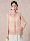Model wearing a pink 100% silk organza vest with floral embroidery, holding a bag, paired with a white pleated skirt.