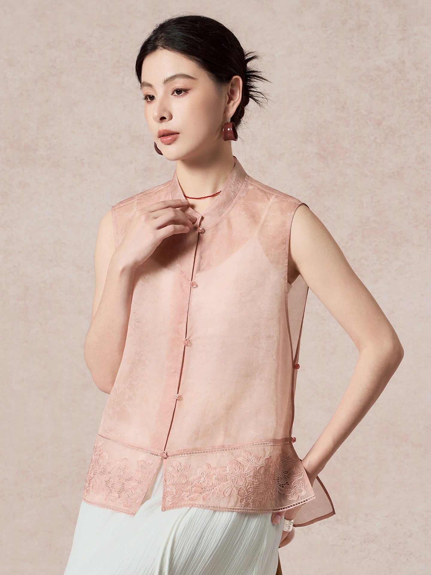 Front view of a pink sheer silk vest with a mandarin collar, delicate cutwork embroidery, and front button closure, showcasing the elegant New Chinese style.